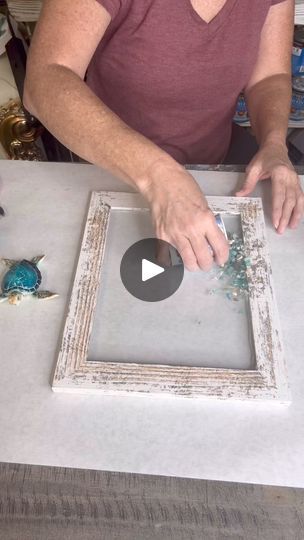 a woman is working on an old window frame with glass and beads in the center