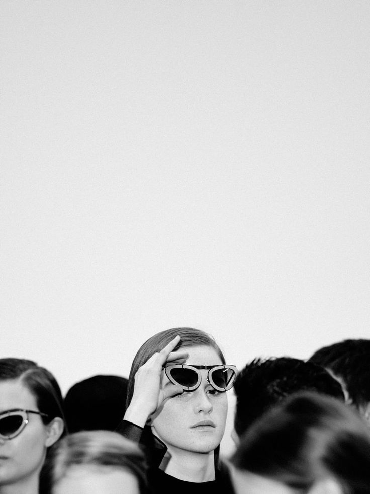 a black and white photo of a woman with sunglasses on her head in front of a group of people