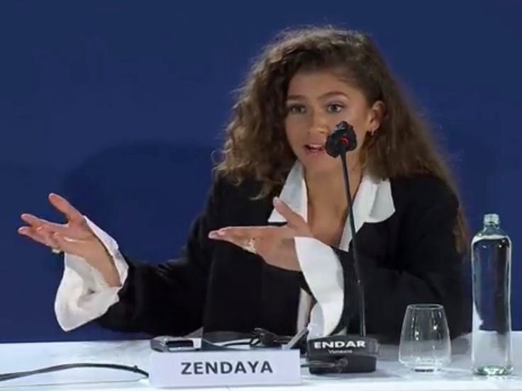 a woman sitting at a table in front of a microphone