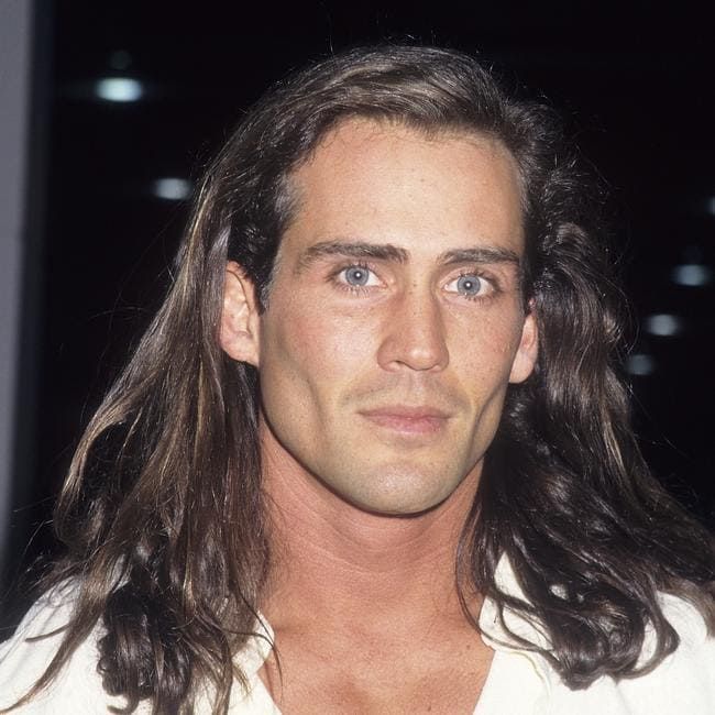 a man with long hair wearing a white shirt