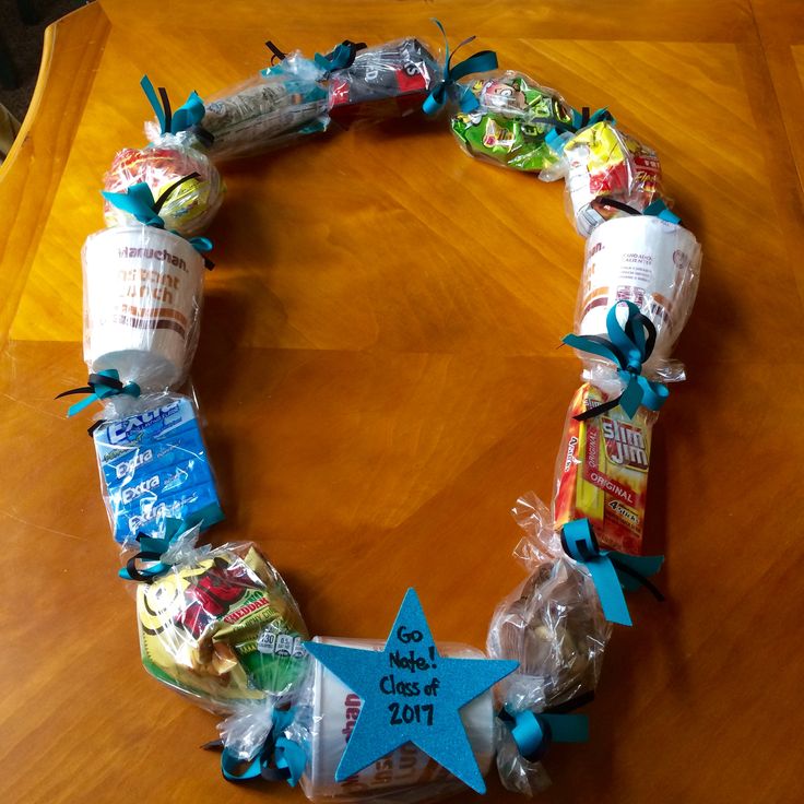 a wreath made out of candy wrapped in plastic wrap and tied to a wooden table