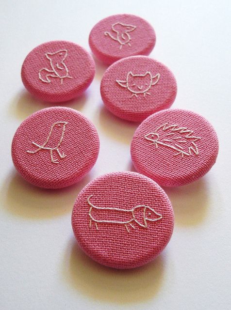 six pink buttons with embroidered designs on them