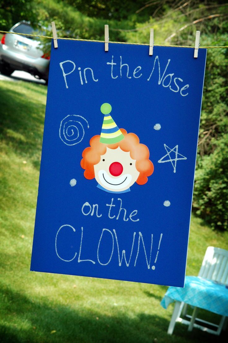 a sign that says pin the nose on the clown hanging from a clothes line outside