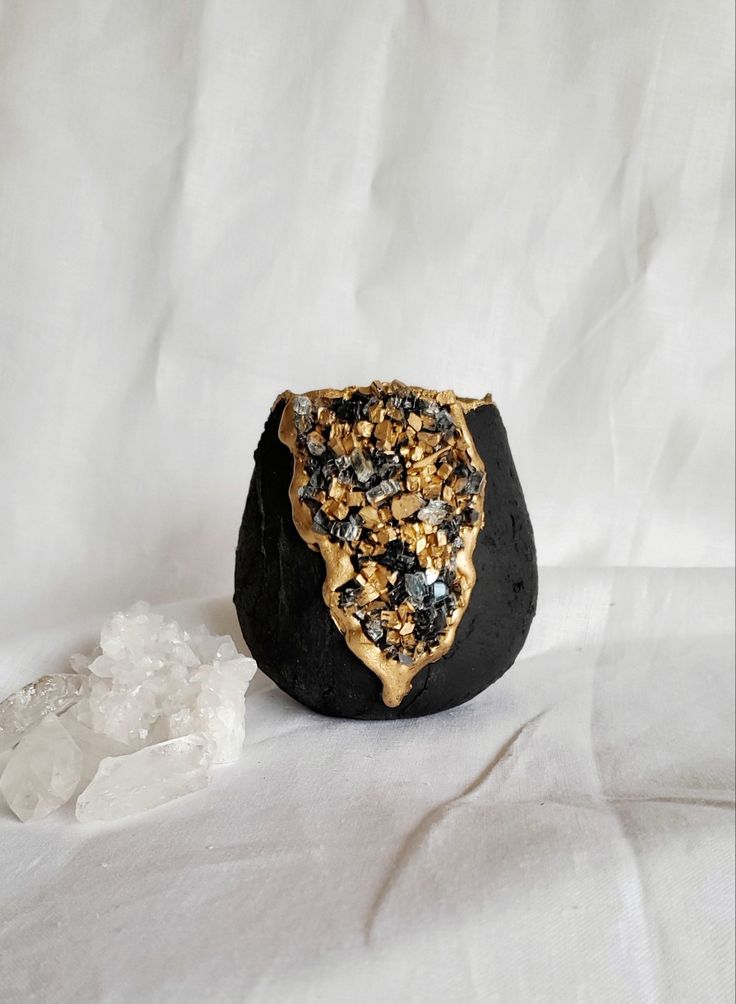 a black rock with gold flecks on it and some white rocks around it