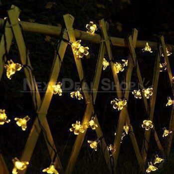 a fence with flowers on it is lit up by lights that are attached to the posts