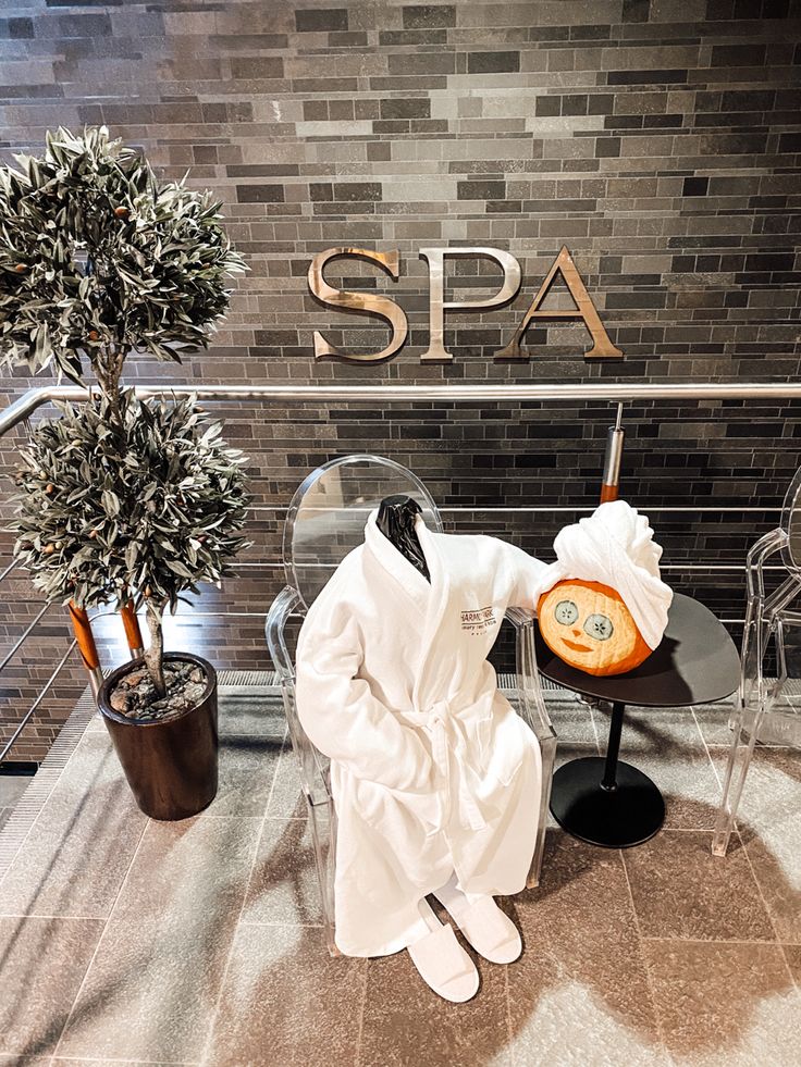 a white robe sitting on top of a chair next to a potted plant