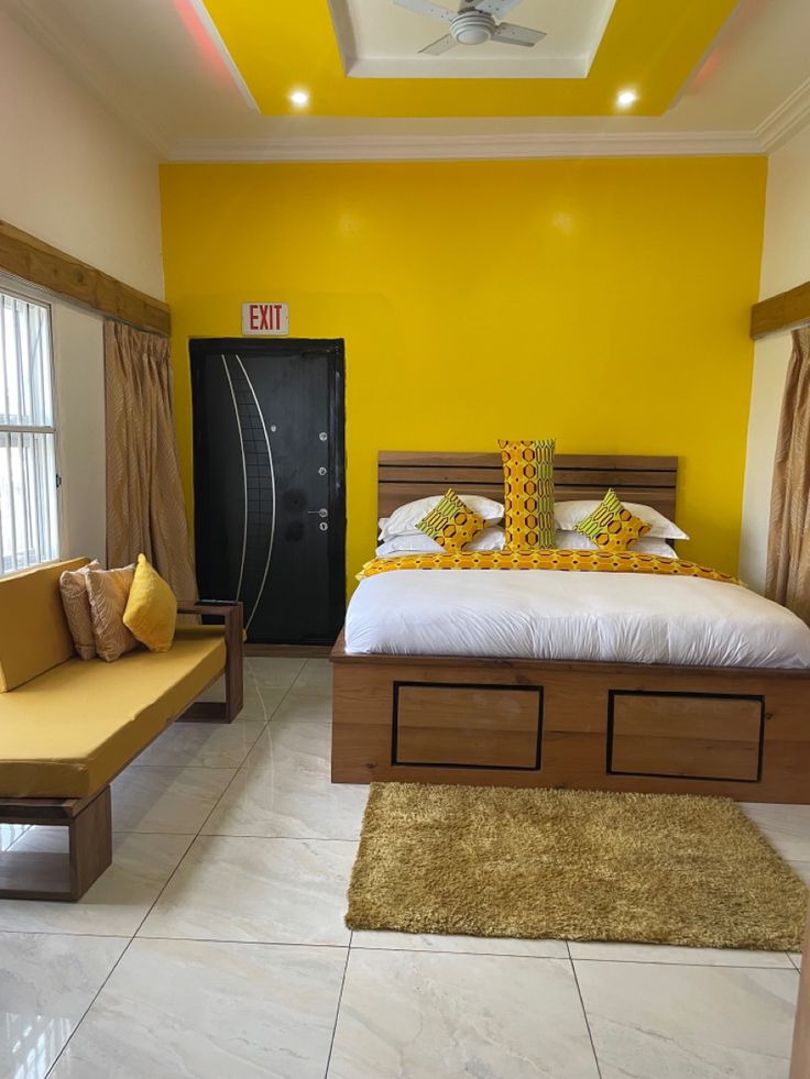 a bed room with a neatly made bed and yellow walls