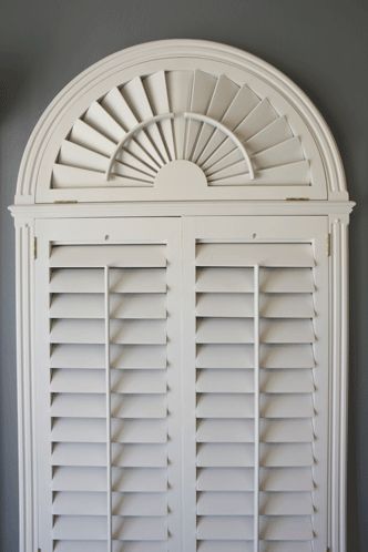 an arched window with shutters on the side