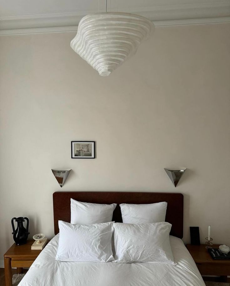 a bed with white sheets and pillows in a bedroom