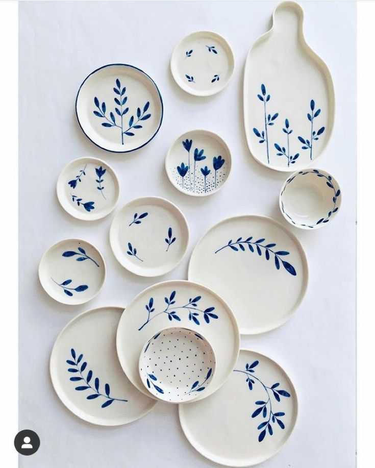 the blue and white dishes are arranged on top of each other, with leaves painted on them