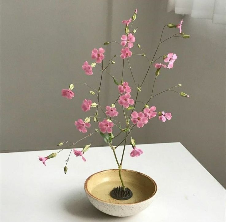 a vase with pink flowers in it sitting on a white counter top next to a window