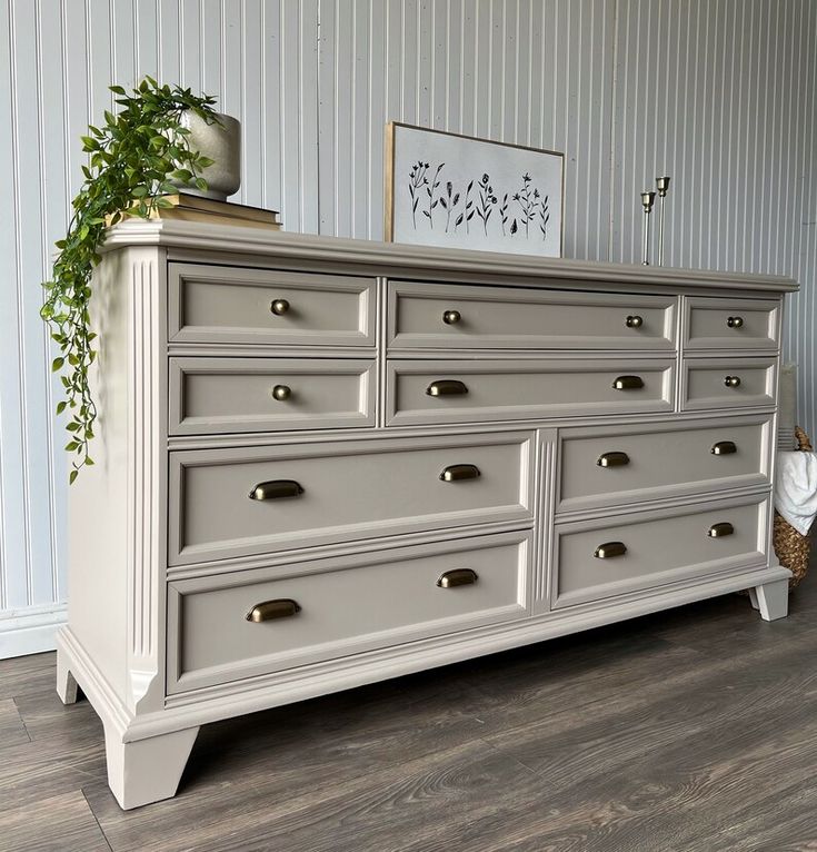 a white dresser with drawers and a potted plant on top