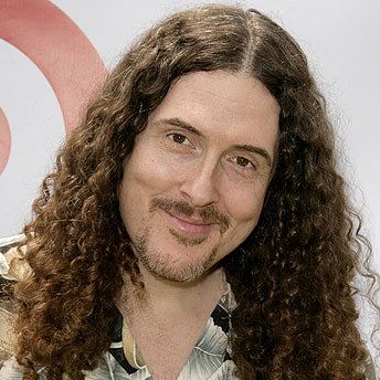 a man with long curly hair smiling at the camera