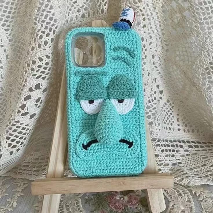 a crocheted phone case with an angry face on it