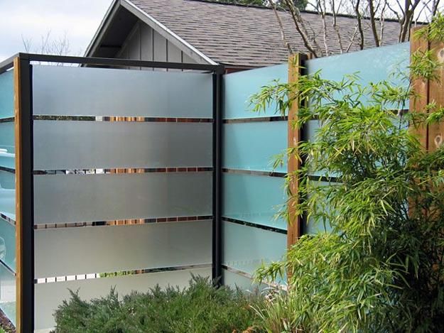 an outdoor privacy fence in front of a house with trees and bushes around it,