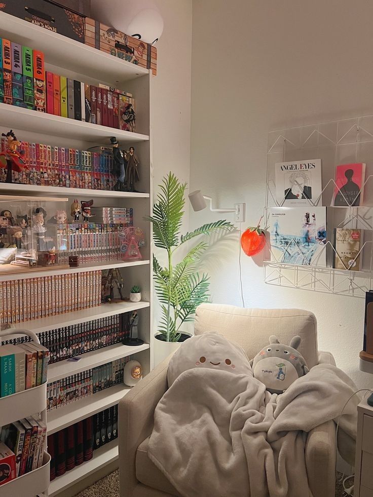 a living room filled with lots of books on shelves next to a white couch covered in a blanket