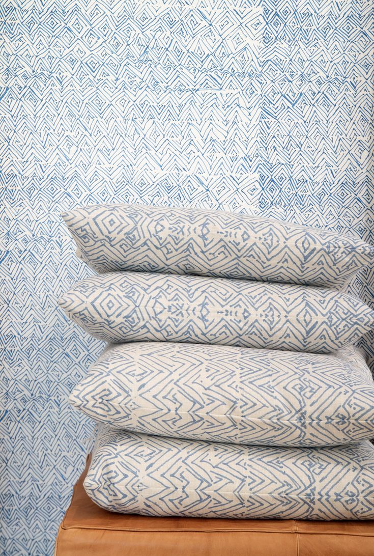 four pillows stacked on top of each other in front of a blue and white wall