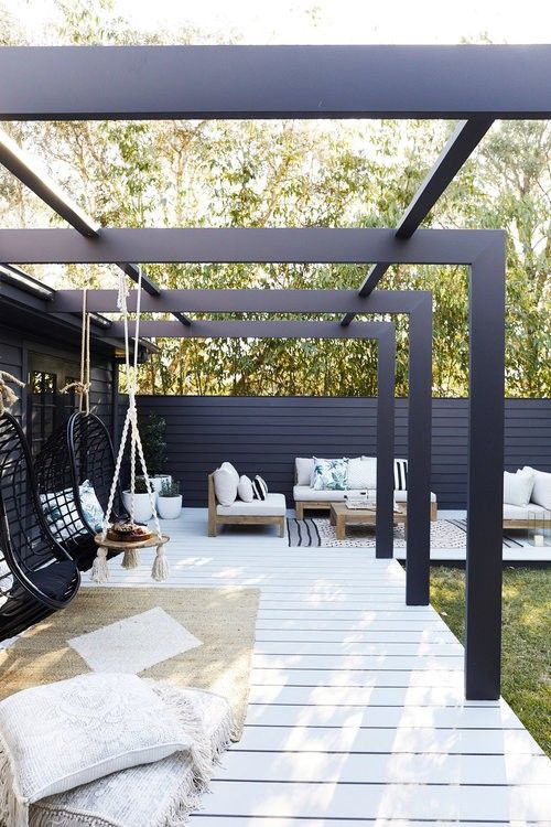 an outdoor patio with hanging chairs and rugs