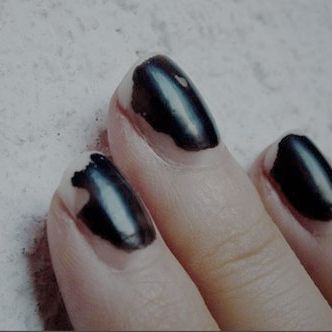 a woman's hand with black nail polish on it