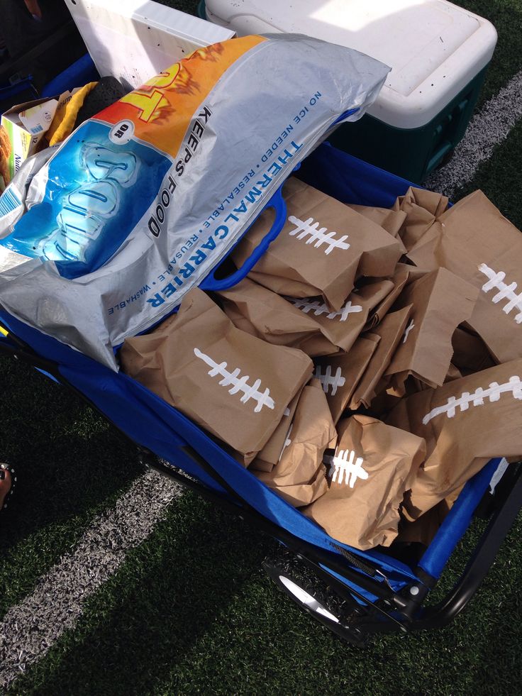 a blue cart filled with bags and sports balls on top of a grass covered field