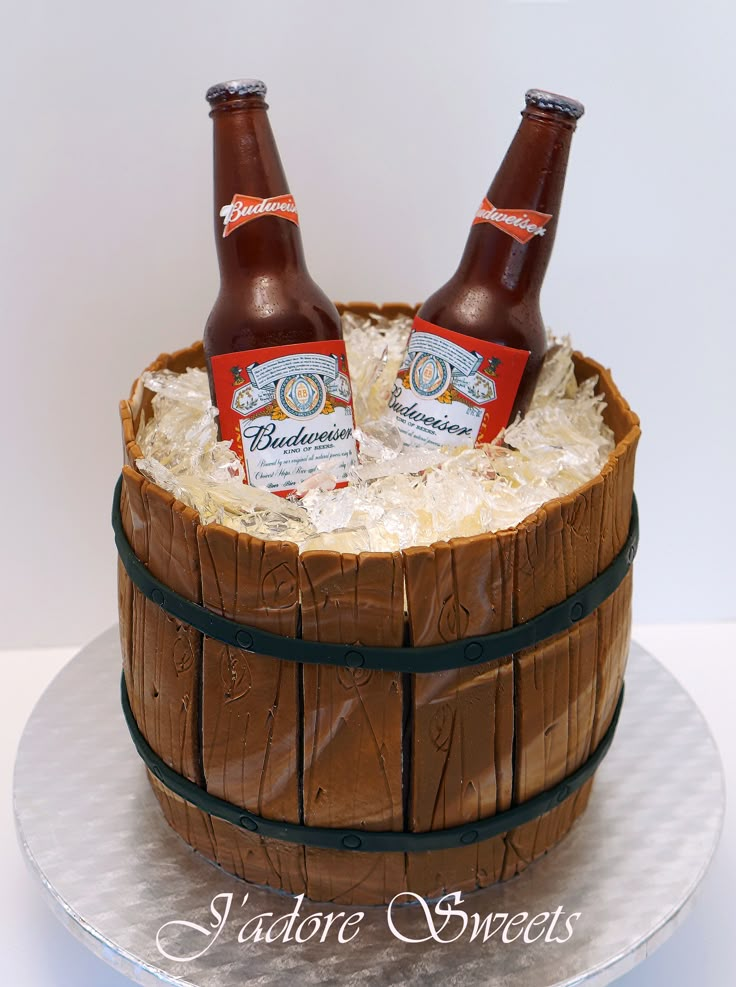 two beer bottles sitting on top of a barrel cake