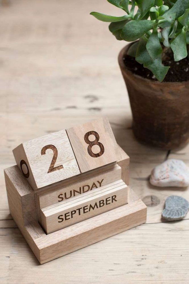 a wooden calendar sitting next to a potted plant