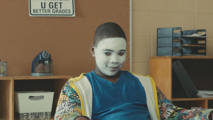 a boy with white face paint sitting in a chair