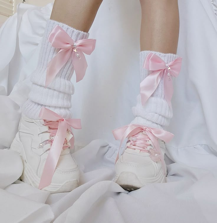 white leg warmers with pink bows. Each bow has a danggling chain with pearl and pink crystal heart beads. Model is wearing these leg warmers with chunky white platforms with pink ribbions as the shoe laces. There is a bunny charm with angel wings and heart charm on one shoe and a pink translucent my melody charm and a cat paw charm on the other shoe. Pastel Leg Warmers, Bow Leg Warmers, Shoes With Leg Warmers, Cute Pink Clothes, Leg Warmers Shoes, Kawaii Clothes Pastel, Cute Pastel Clothes, Leg Warmers Aesthetic, Cute Pink Shoes