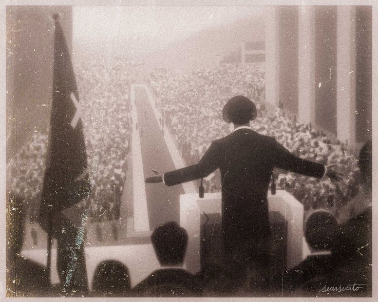 a man standing at a podium in front of an audience with his arms wide open