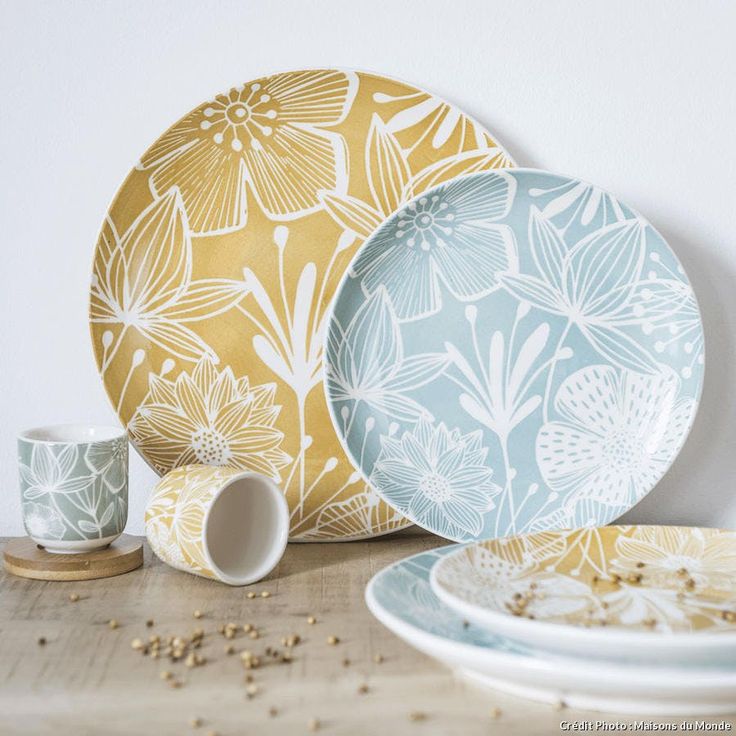 plates, cups and saucers on a table with flowers painted on the plates next to them