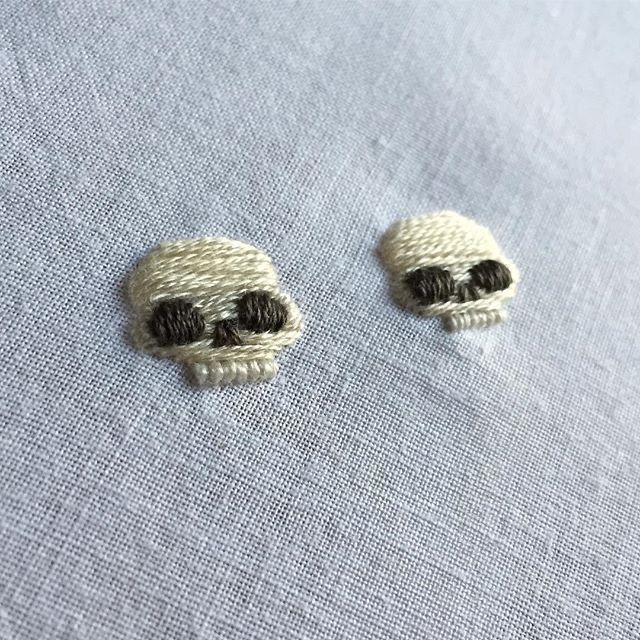 two small knitted skulls sitting on top of a white cloth