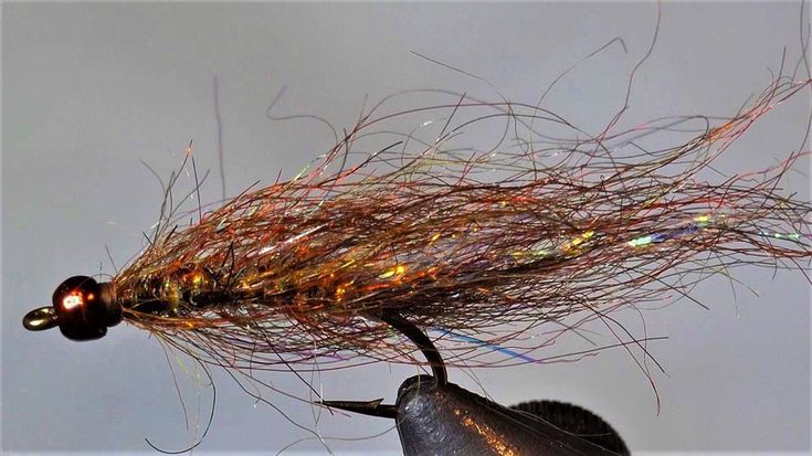 a close up of a fishing lure on a person's hand with water in the background