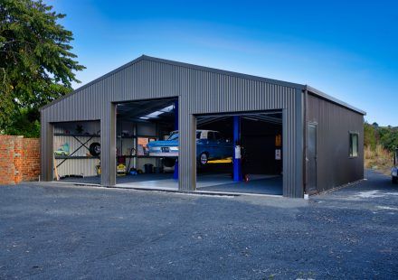 two cars are parked in an open garage