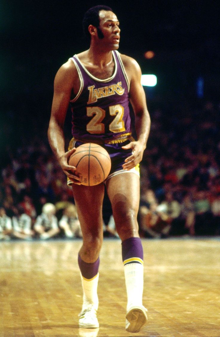 a man holding a basketball on top of a court