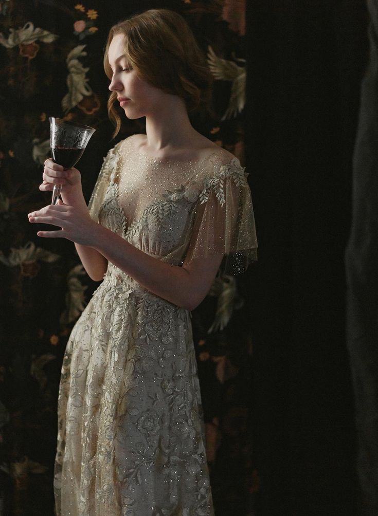 a woman in a white dress holding a glass of wine