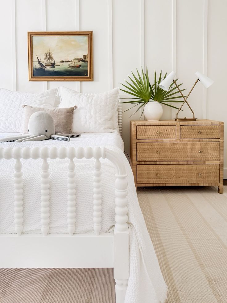 a bedroom with white bedding and wooden dresser