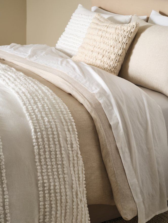 a bed with white linens and pillows on it