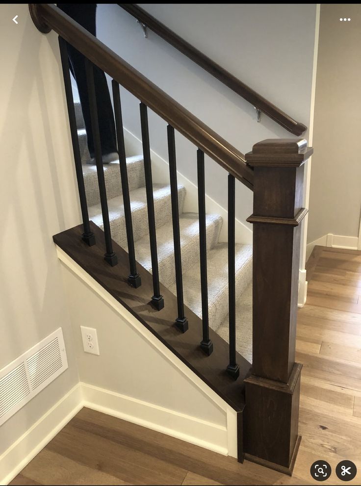 the stairs are made of wood and have black railings on each handrail, along with carpeted flooring