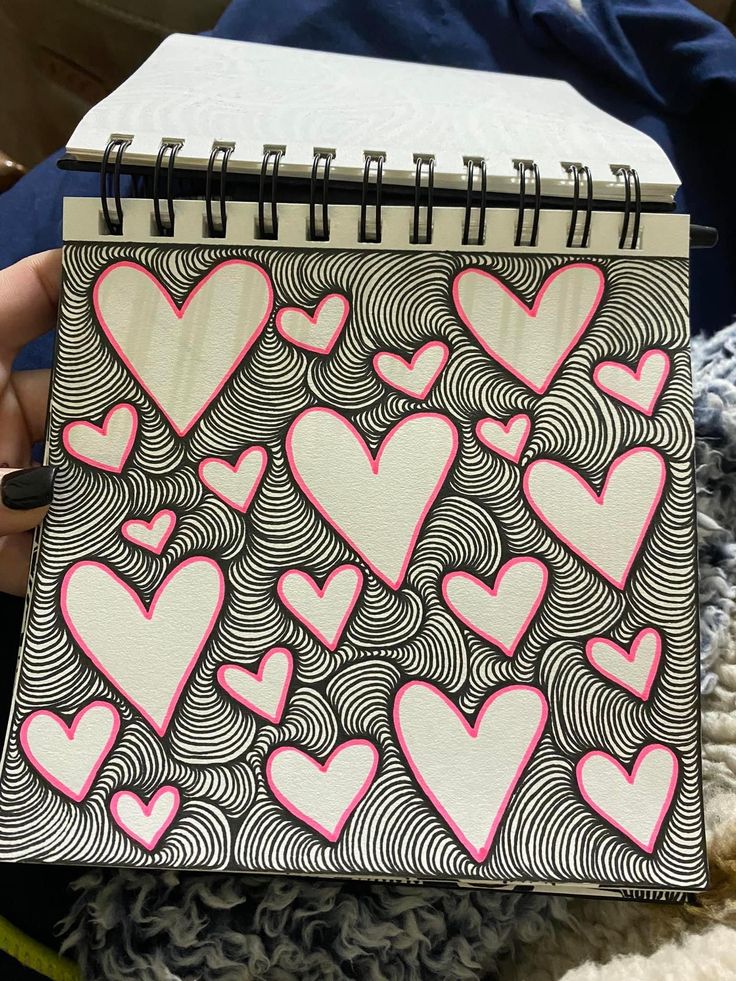 someone holding up a notebook with hearts on it