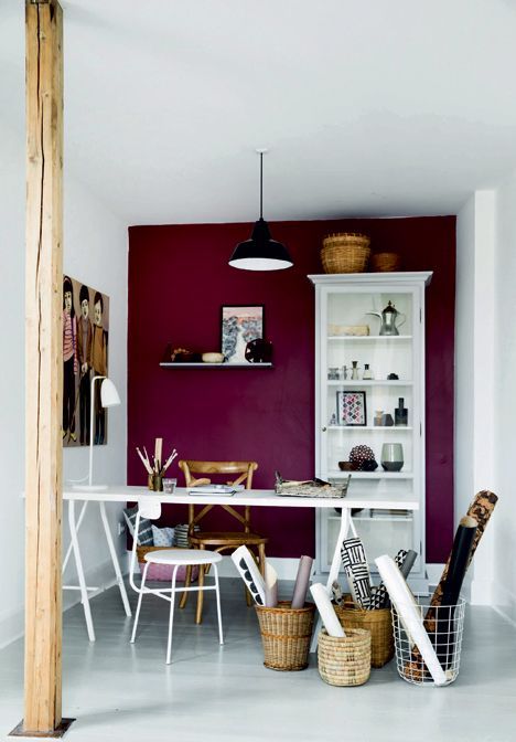 a dining room with red walls and white furniture in the center, along with wicker baskets on the floor