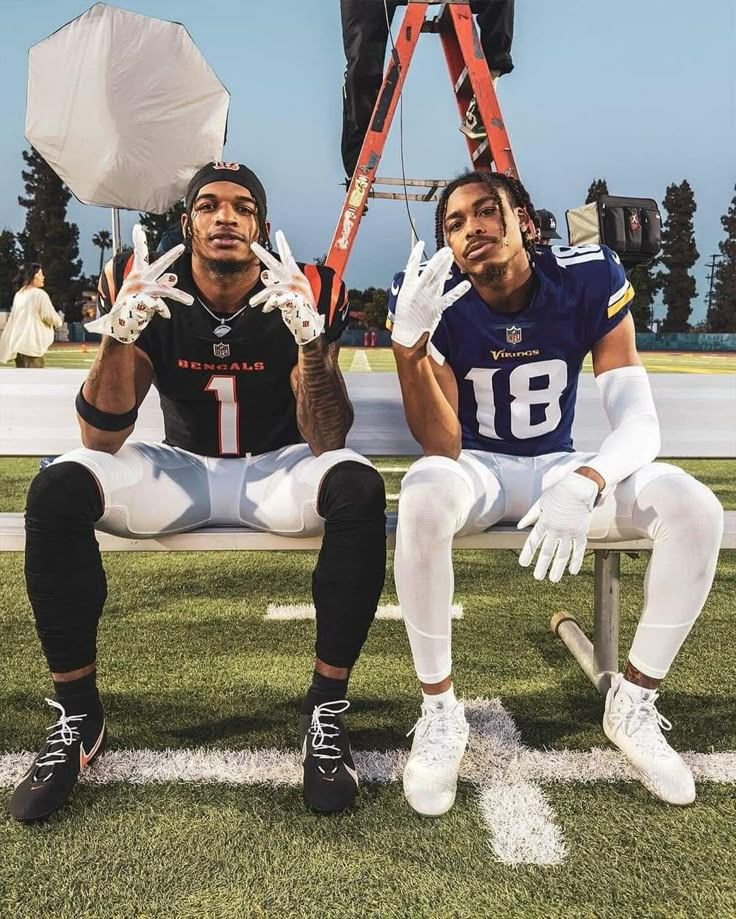 two football players sitting on a bench with their hands in the air