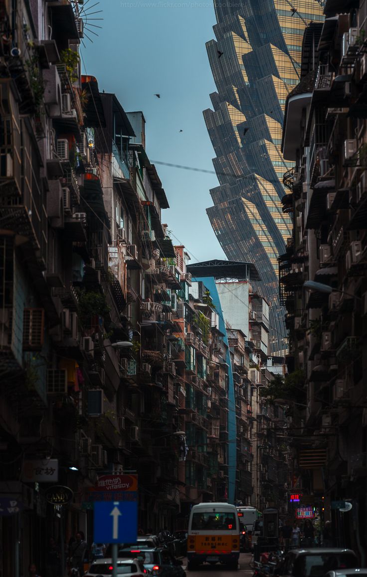 a city street filled with lots of tall buildings and cars driving down the middle of it