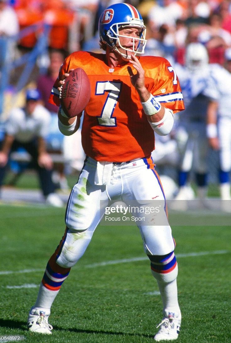 an orange and white football player holding a ball in his hand while standing on the field