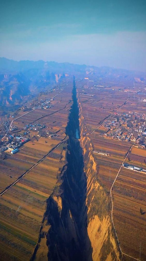 an aerial view of the mountains and plains with a long shadow in the foreground