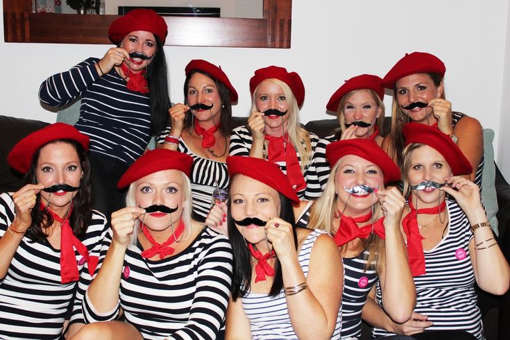 a group of women with fake moustaches on their faces posing for a photo