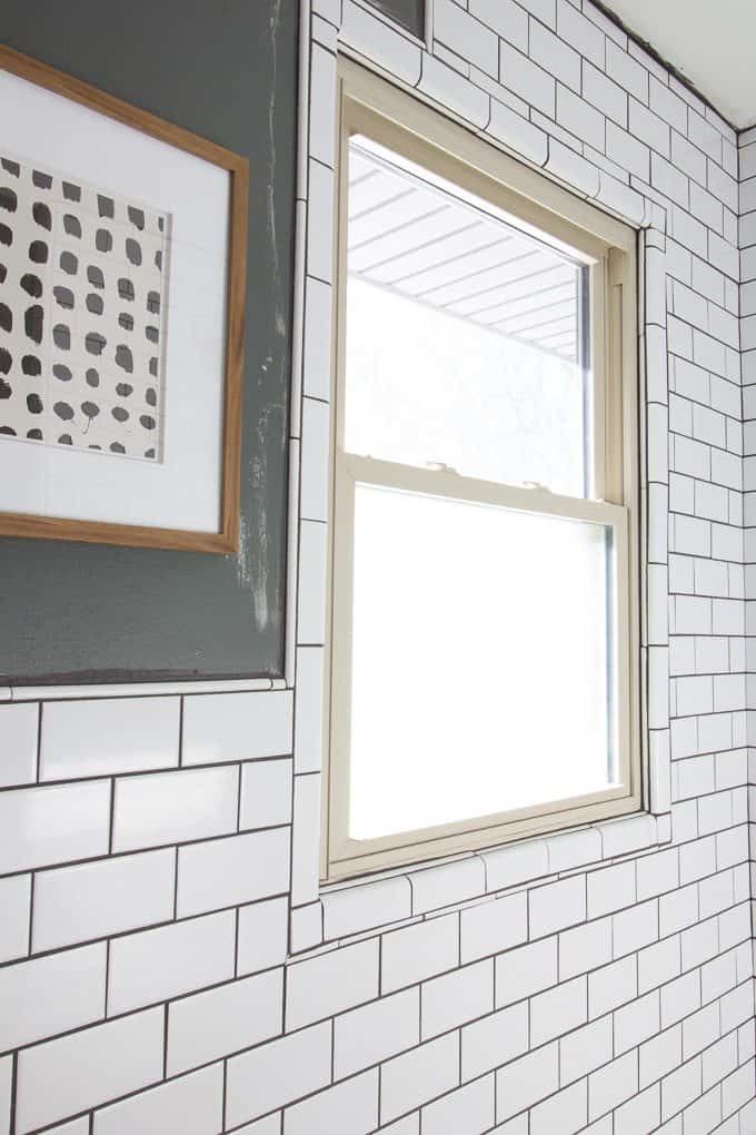 a bathroom with white tile and gray walls