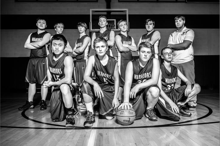 a group of young men sitting on top of a basketball court next to each other