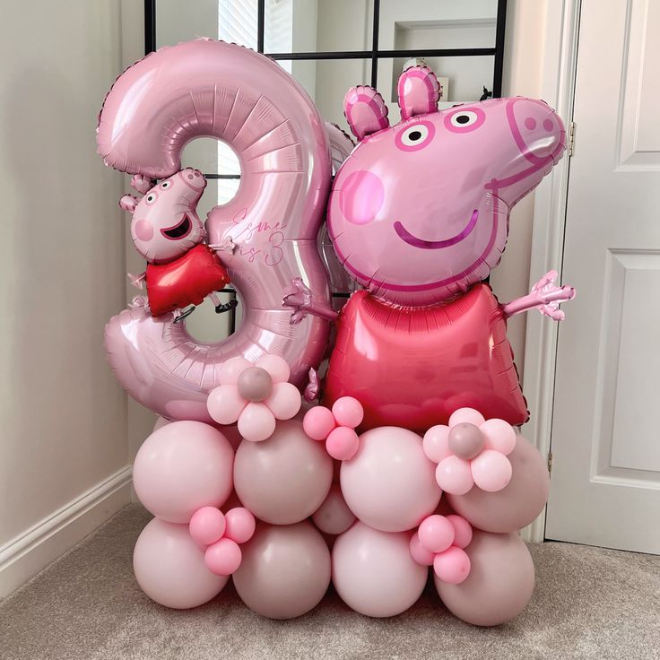 a pink balloon shaped like a pig holding a red heart