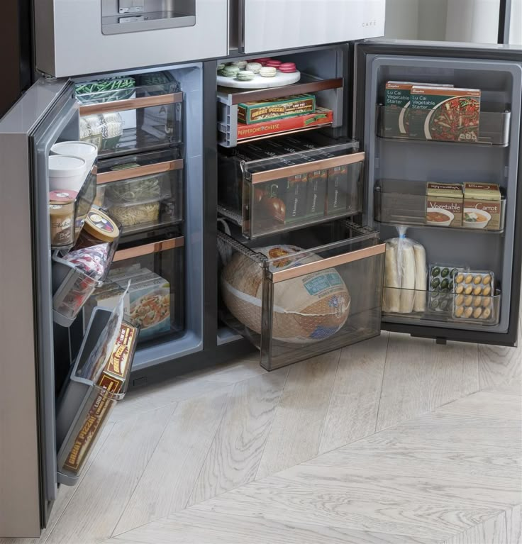 the refrigerator door is open and it has many food items in its drawer, including bread