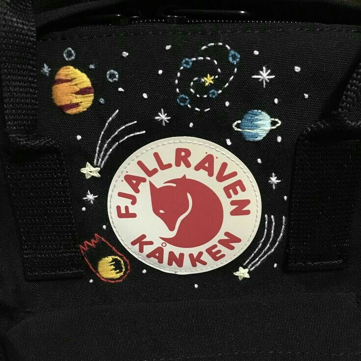 the back pocket of a black backpack with an embroidered sticker on it's side